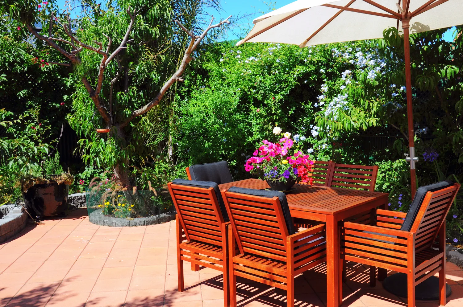 Garden patio with outdoor dining table, chairs and umbrella